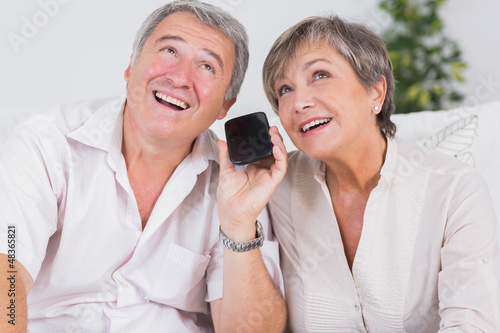 Photo: Old couple listening to a smartphone Old couple listening to a smartphone
