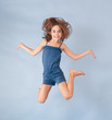 Photo: cheerful girl jumping on a blue background cheerful girl jumping on a blue background