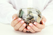 Woman hands with money in glass jar, close up