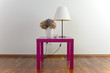 Violetter Tisch mit weißer Stehlampe und Blumenvase - Deko
