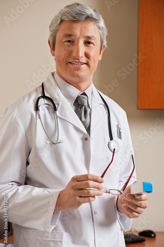 Photo: Doctor Holding Glasses And Medicine Box Doctor Holding Glasses And Medicine Box