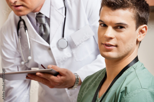 Photo: Male Technician With Doctor In Background Male Technician With Doctor In Background