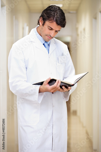 Photo: Doctor Reading Journal In Hospital Corridor Doctor Reading Journal In Hospital Corridor