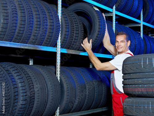 Photo: Car mechanic looking for a tire in a tire store Car mechanic looking for a tire in a tire store