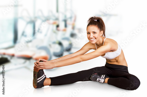 Photo: Beautiful young brunette doing stretching the muscles at the gym Beautiful young brunette doing stretching the muscles at the gym