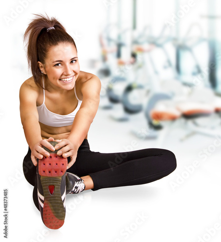 Photo: Beautiful young brunette doing stretching the muscles at the gym Beautiful young brunette doing stretching the muscles at the gym