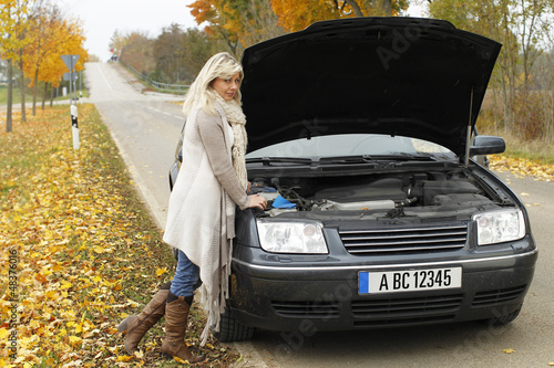 Photo: Frau steht ratlos an der Motorhaube bei Panne Frau steht ratlos an der Motorhaube bei Panne