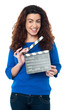 Cute woman in blue attire holding clapperboard