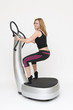 Eine junge sportliche Frau trainiert stehend auf Powerplate