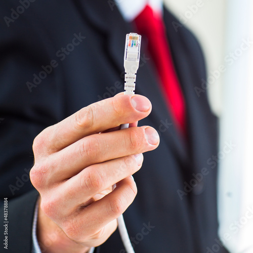 Photo: Young businessman holding an ethernet cable Young businessman holding an ethernet cable