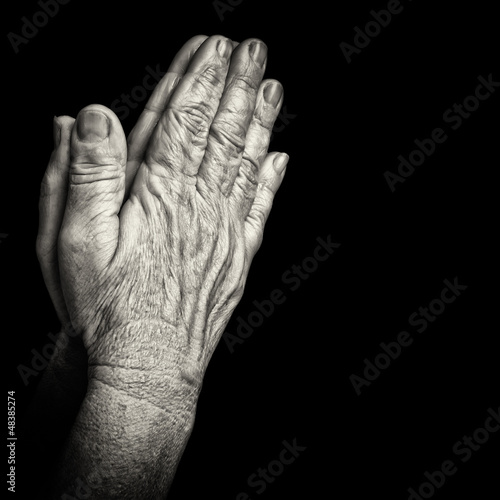 Photo: Old wrinkled hands praying isolated on black Old wrinkled hands praying isolated on black
