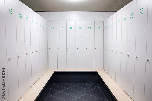 Photo: Gym dressing room with lots of white lockers with green numbers Gym dressing room with lots of white lockers with green numbers