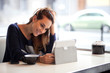 Candid image of a young woman using tablet computer in a coffee