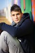 Photo: Handsome young man sitting against colorful graffiti Handsome young man sitting against colorful graffiti