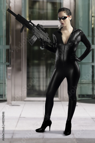 Photo: Sexy woman holding gun wearing a black leather dress Sexy woman holding gun wearing a black leather dress