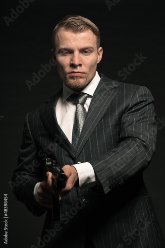 Photo: Mafia man in suit with cocaine and rifle. Studio shot. Mafia man in suit with cocaine and rifle. Studio shot.