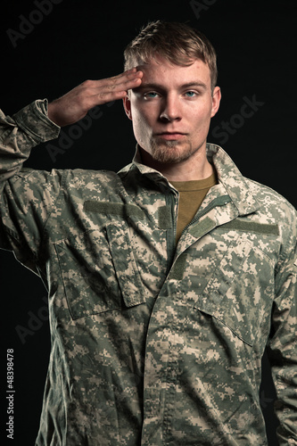 Photo: Military young man salutes. Studio portrait. Military young man salutes. Studio portrait.