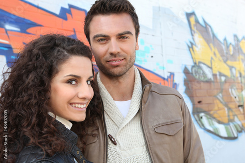 Photo: young couple in front of a graffiti wall young couple in front of a graffiti wall