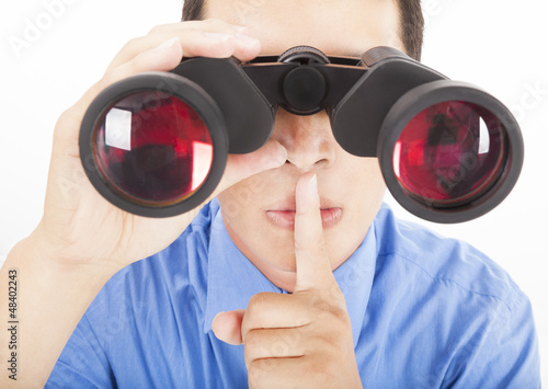 Photo: man looks through binoculars with silent gesture man looks through binoculars with silent gesture