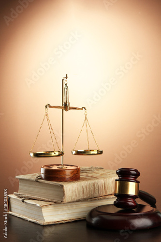 Photo: Golden scales of justice, gavel and books on brown background Golden scales of justice, gavel and books on brown background