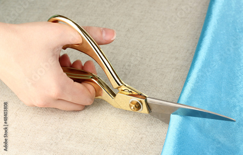 Photo: Seamstress cut blue fabric on beige fabric background Seamstress cut blue fabric on beige fabric background