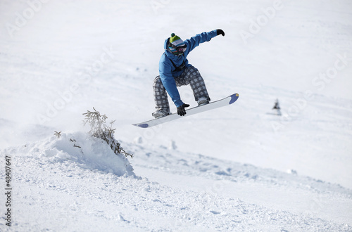 Photo: Young male snowboarder jumping on a snowy slope Young male snowboarder jumping on a snowy slope