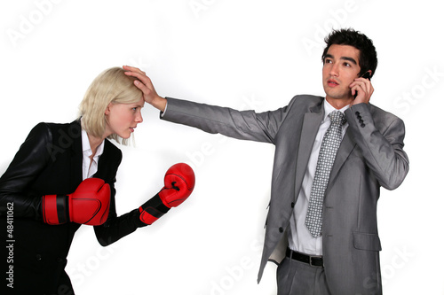 Photo: businesswoman with boxing gloves and colleague on phone businesswoman with boxing gloves and colleague on phone