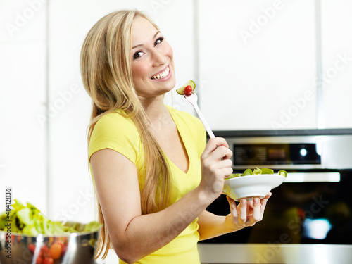 Photo: Pretty girl in the kitchen eating healthy food to lose weight Pretty girl in the kitchen eating healthy food to lose weight