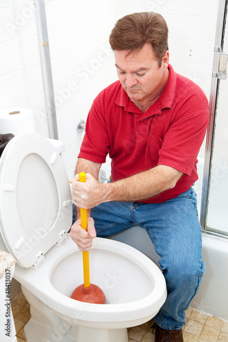 Photo: Man Uses Plunger on Clogged Toilet Man Uses Plunger on Clogged Toilet