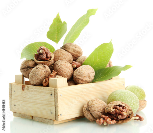 Photo: walnuts with green leaves in woooden crate, isolated on white walnuts with green leaves in woooden crate, isolated on white
