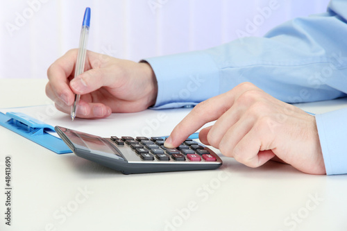 Photo: Closeup of businessman hands with calculator Closeup of businessman hands with calculator