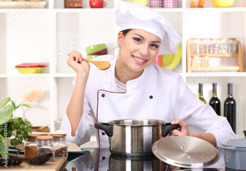 Photo: Young woman chef cooking in kitchen Young woman chef cooking in kitchen