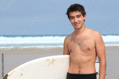 Photo: Young man at the beach with surfboard Young man at the beach with surfboard