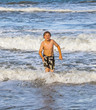 young boy running through the water at the beach