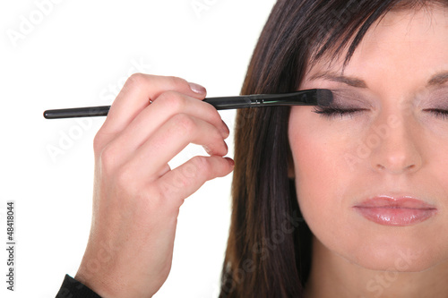 Photo: beautiful woman putting some eye shadow beautiful woman putting some eye shadow