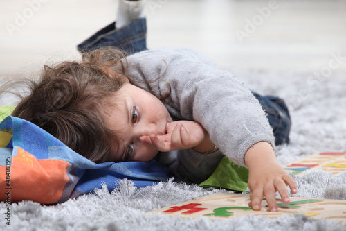 Photo: Child lying on the floor playing with a puzzle Child lying on the floor playing with a puzzle
