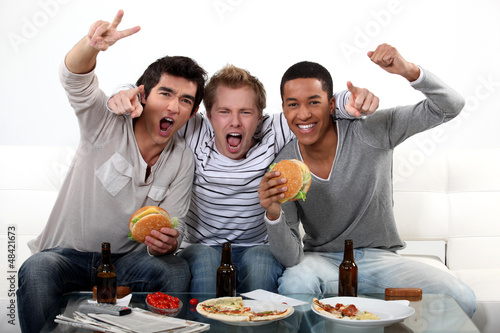 Photo: three friends eating while watching television three friends eating while watching television