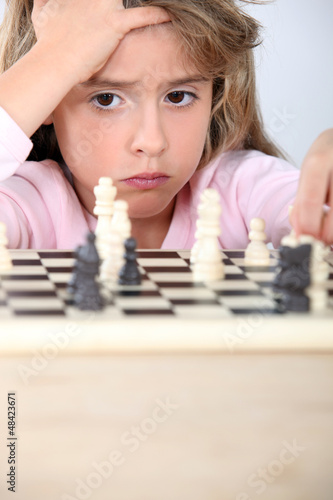 Photo: little girl playing chess little girl playing chess