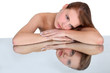 Woman resting head on reflective surface