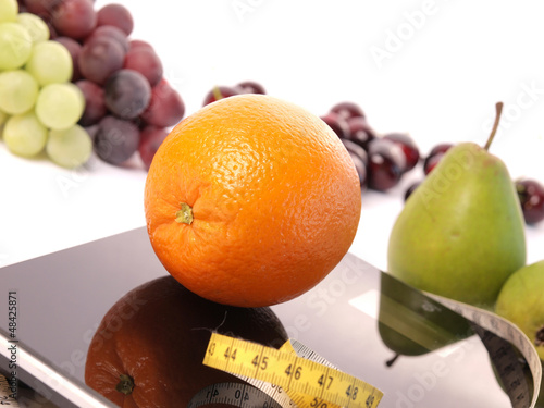 Photo: Scale with an orange fruit and a measuring tape Scale with an orange fruit and a measuring tape
