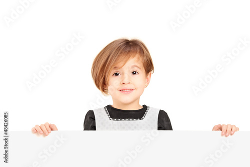 Photo: Little smiling girl standing behind a blank panel Little smiling girl standing behind a blank panel