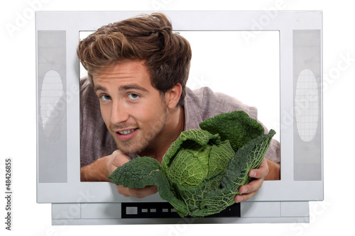 Photo: Man holding cabbage escaping from television Man holding cabbage escaping from television