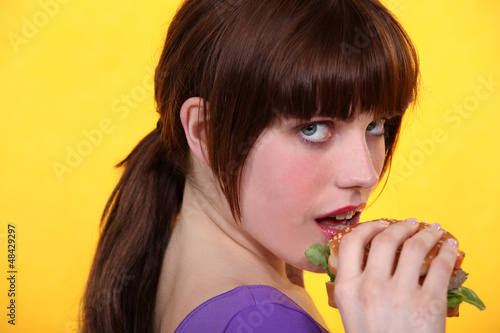 Photo: Young brown-haired woman eating a hamburger Young brown-haired woman eating a hamburger