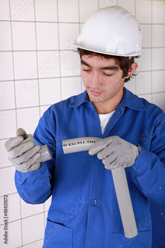Photo: Young plumber with plastic pipe Young plumber with plastic pipe