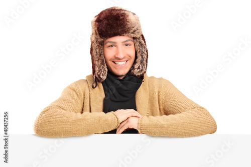 Photo: Handsome young man with fur hat posing behing a panel Handsome young man with fur hat posing behing a panel