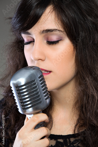 Photo: Attractive young woman with a retro microphone Attractive young woman with a retro microphone