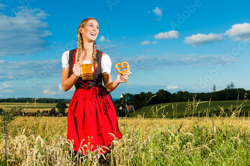 Photo: Junge Frau trinkt Bier und hält Brezel Junge Frau trinkt Bier und hält Brezel