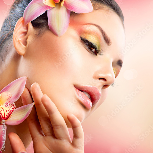 Photo: Beautiful Spa Girl With Orchid Flowers Touching her Face Beautiful Spa Girl With Orchid Flowers Touching her Face