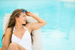 Happy young woman in swimsuit on chaise-longue 