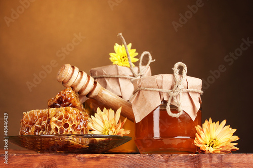 Photo: two jars of honey,honeycombs and wooden drizzler two jars of honey,honeycombs and wooden drizzler